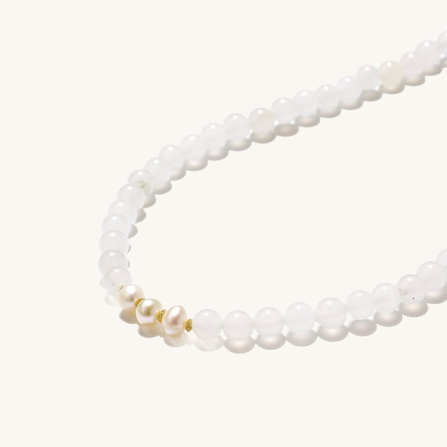 Stretch bracelet with white jade beads, freshwater pearls, and orange agate centerpiece on cream background.