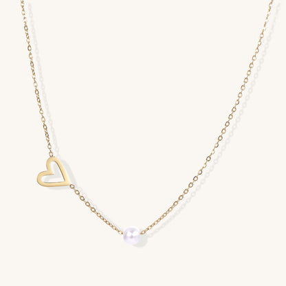 Dainty 14K gold-plated necklace with open heart pendant and white pearl bead on neutral background