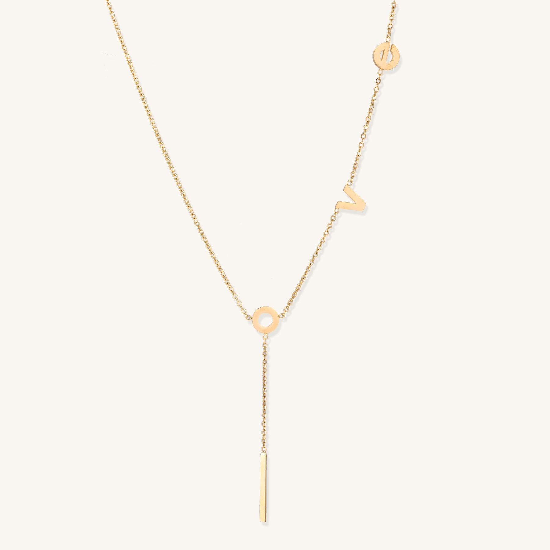 Gold-plated lariat necklace spelling LOVE with letter charms and vertical bar pendant on white background.
