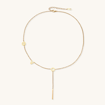 Gold-plated lariat necklace spelling LOVE with letter charms and vertical bar pendant on white background.