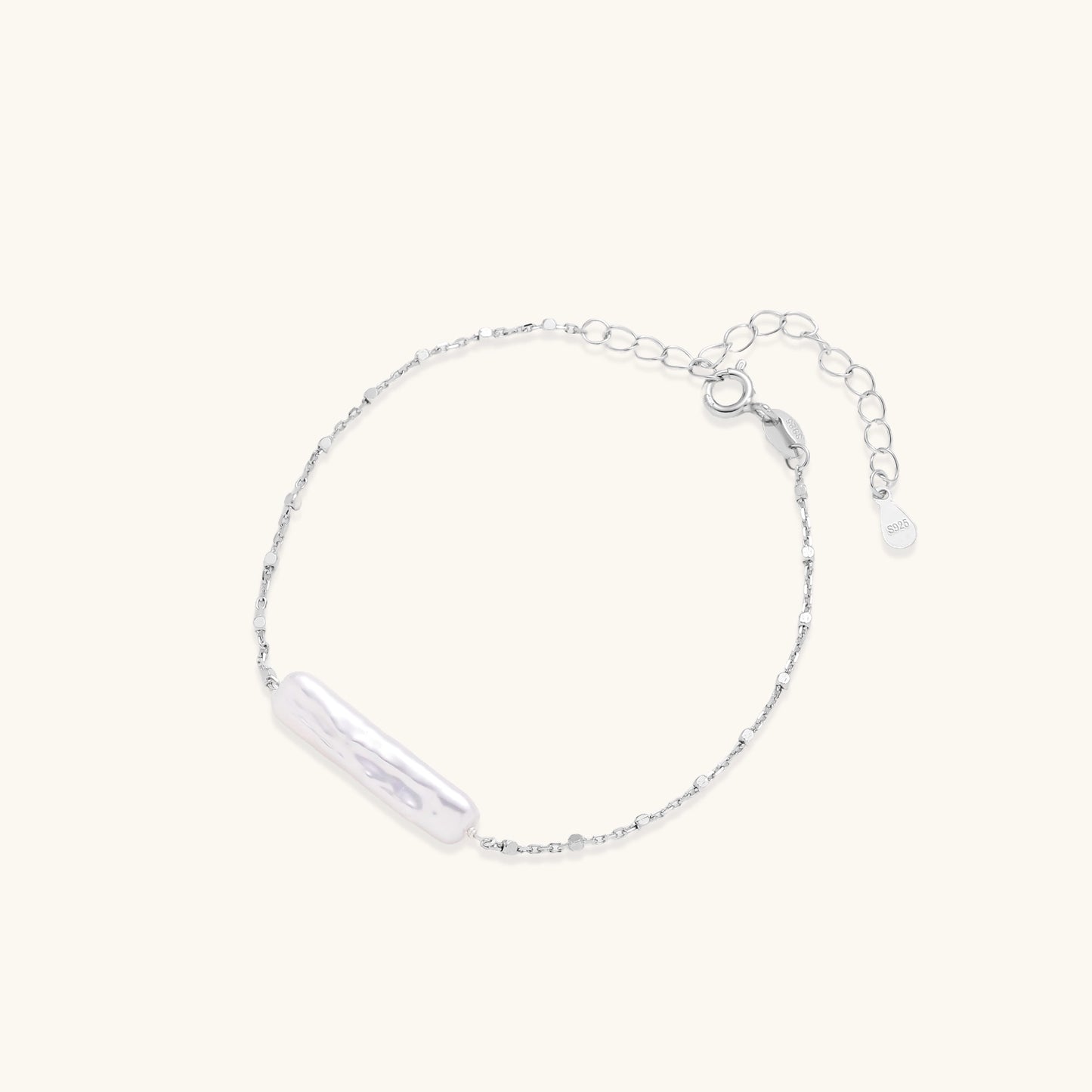 Delicate sterling silver chain bracelet with an organic white baroque pearl centerpiece on neutral background