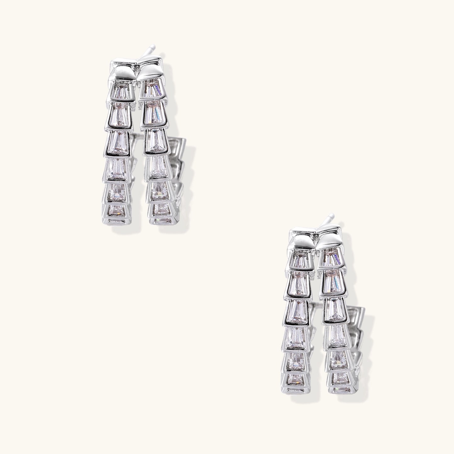 Gold-plated huggie hoops featuring vertical rows of clear baguette zirconia stones in geometric linear design