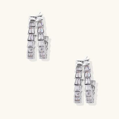 Gold-plated huggie hoops featuring vertical rows of clear baguette zirconia stones in geometric linear design