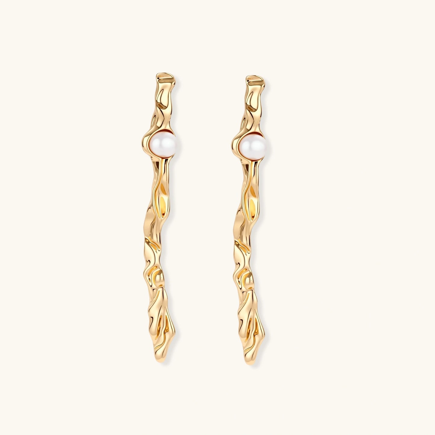 Organic twisted gold-toned drop earrings with white ABS pearls positioned near the top on cream background.